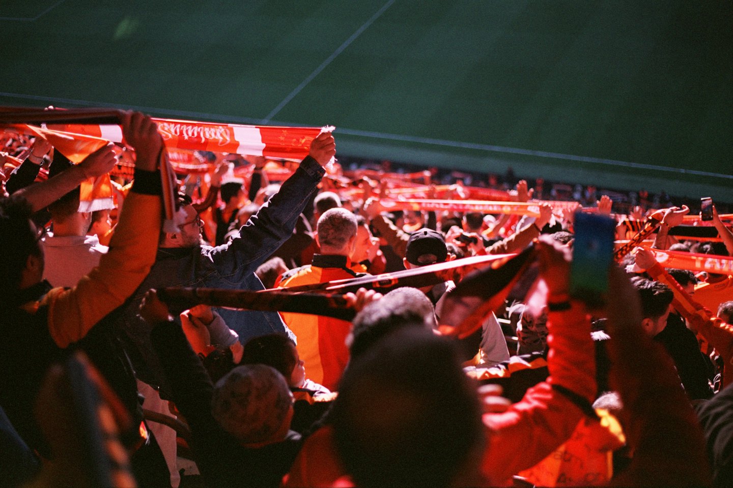 Sports fans cheer while holding Sunderland scarves in a stadium.